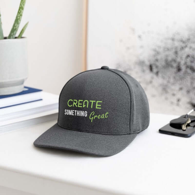Gray cap with 'Create Something Great' text on a desk with office items.
