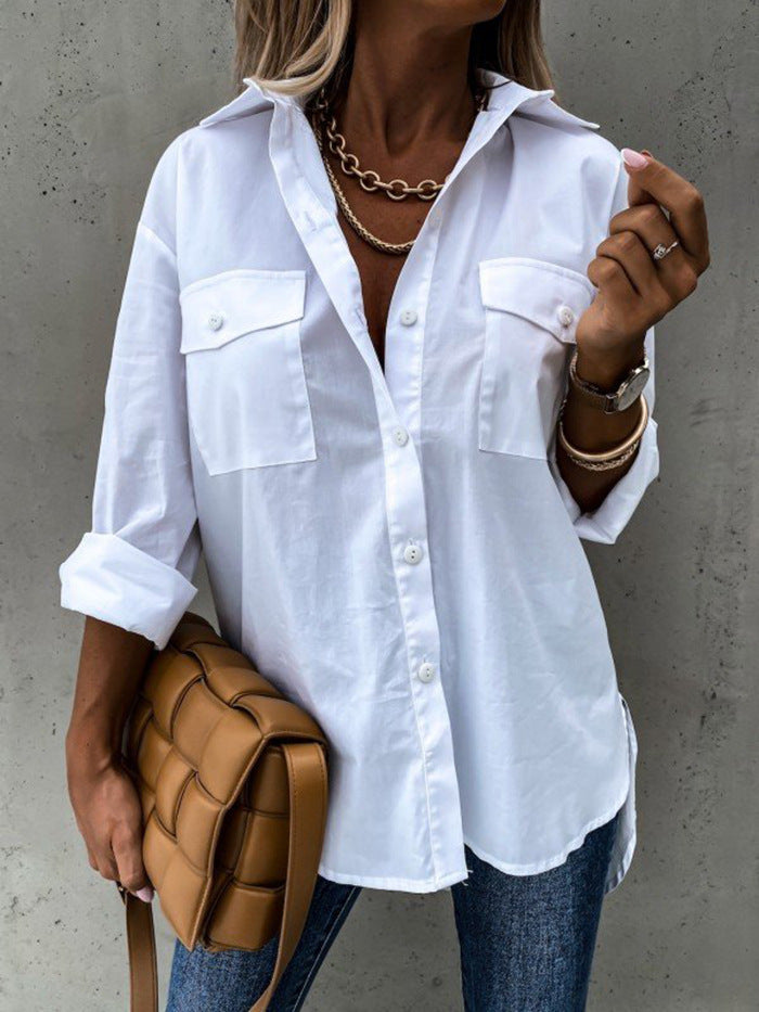 Person wearing a white button-up shirt with rolled-up sleeves, holding a brown bag against a gray background.
