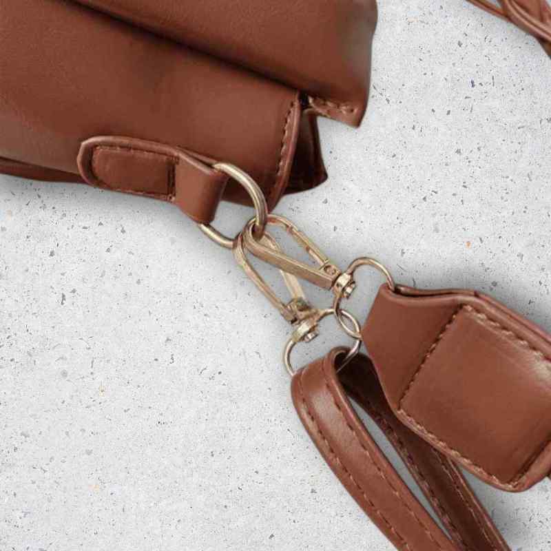 Brown leather bag with a strap on a light gray surface