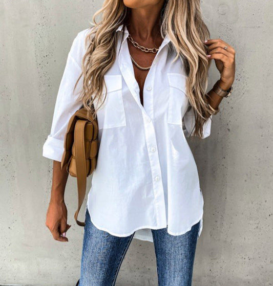 Woman wearing a white shirt and blue jeans against a gray wall.