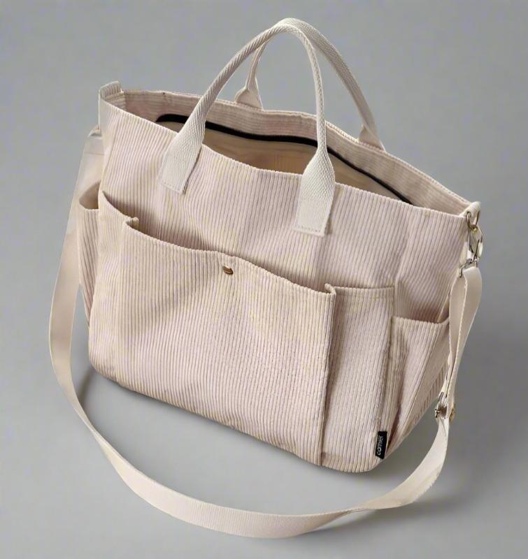 Beige tote bag with multiple pockets and straps on a gray background