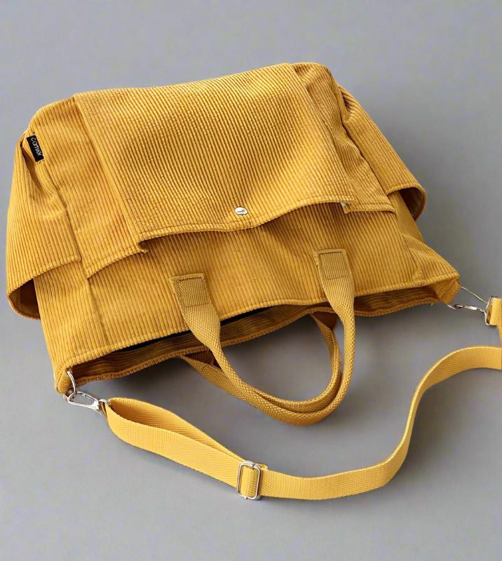 Yellow corduroy bag with a strap on a gray background
