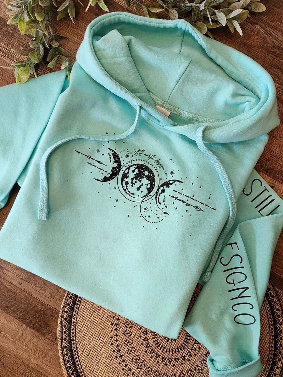 Light blue hoodie with black graphics on a wooden surface