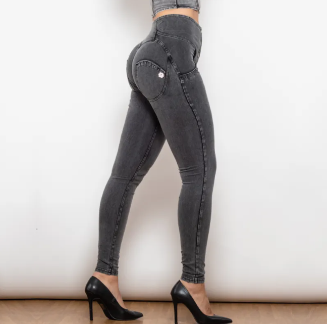 Person wearing black high-waisted jeans and black high heels on a plain background
