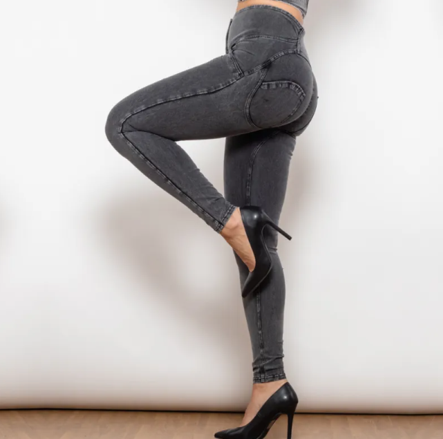 Person wearing black high-waisted jeans and black high-heeled shoes on a white background