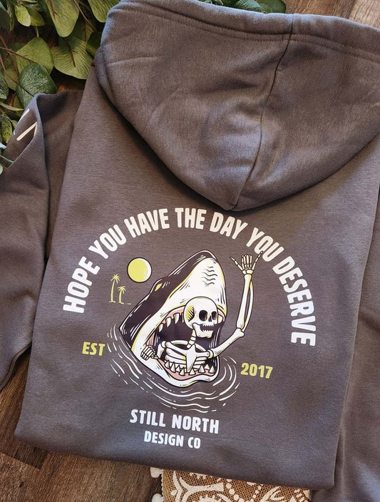 Gray hoodie with a graphic design and text on a wooden surface