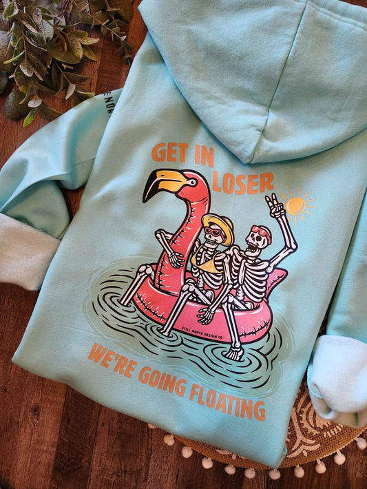 Light blue hoodie with skeleton design and text on a wooden surface