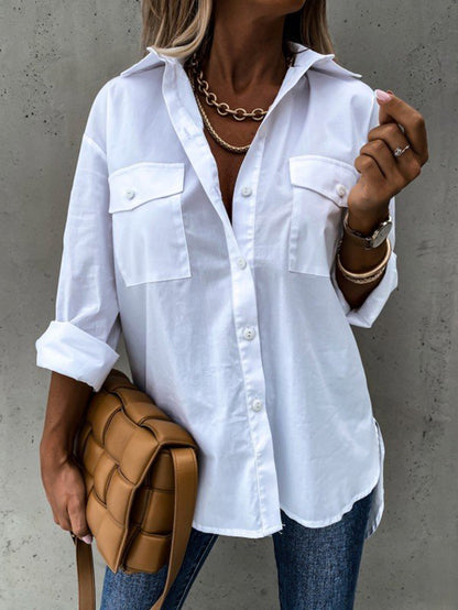 Person wearing a white button-up shirt with rolled-up sleeves, holding a brown bag against a gray background.