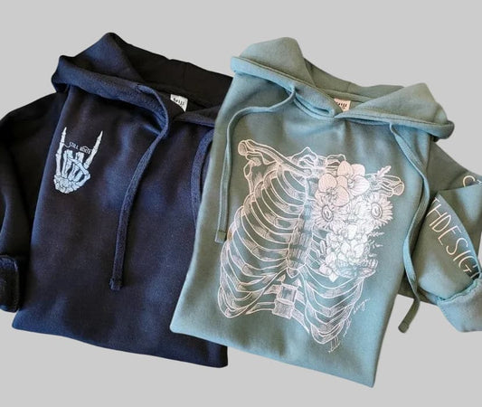 Two hoodies, one navy and one green, with artistic designs on a gray background