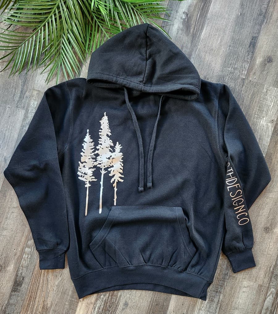 Black hoodie with tree design on a wooden surface