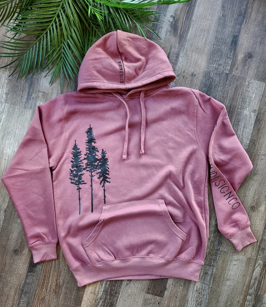 Pink hoodie with tree design on a wooden surface
