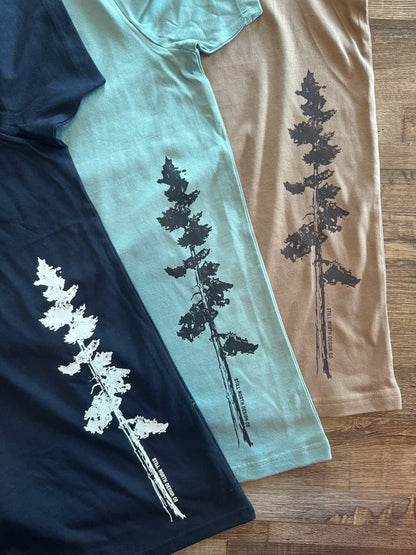 Three t-shirts with tree designs on a wooden surface