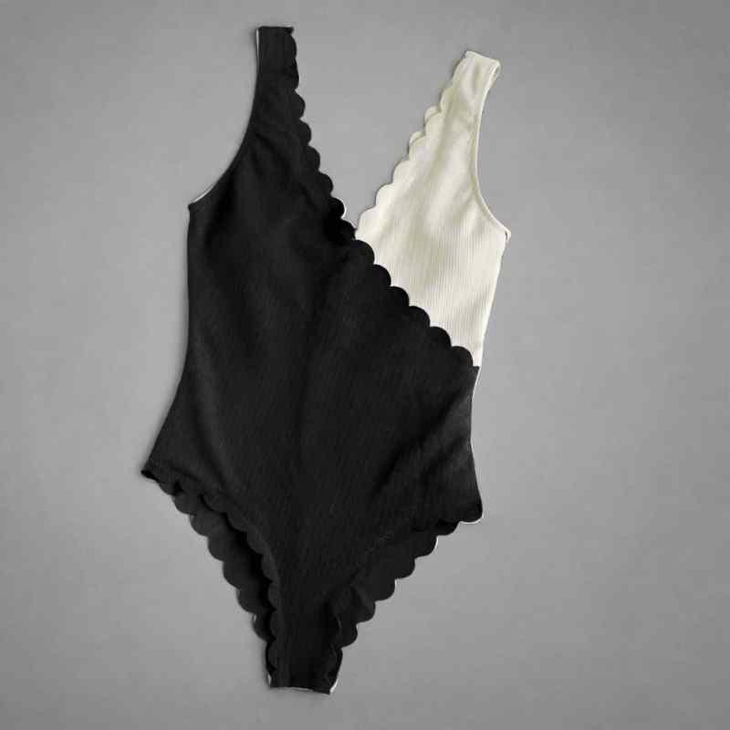 Black and white scalloped swimsuit on a gray background