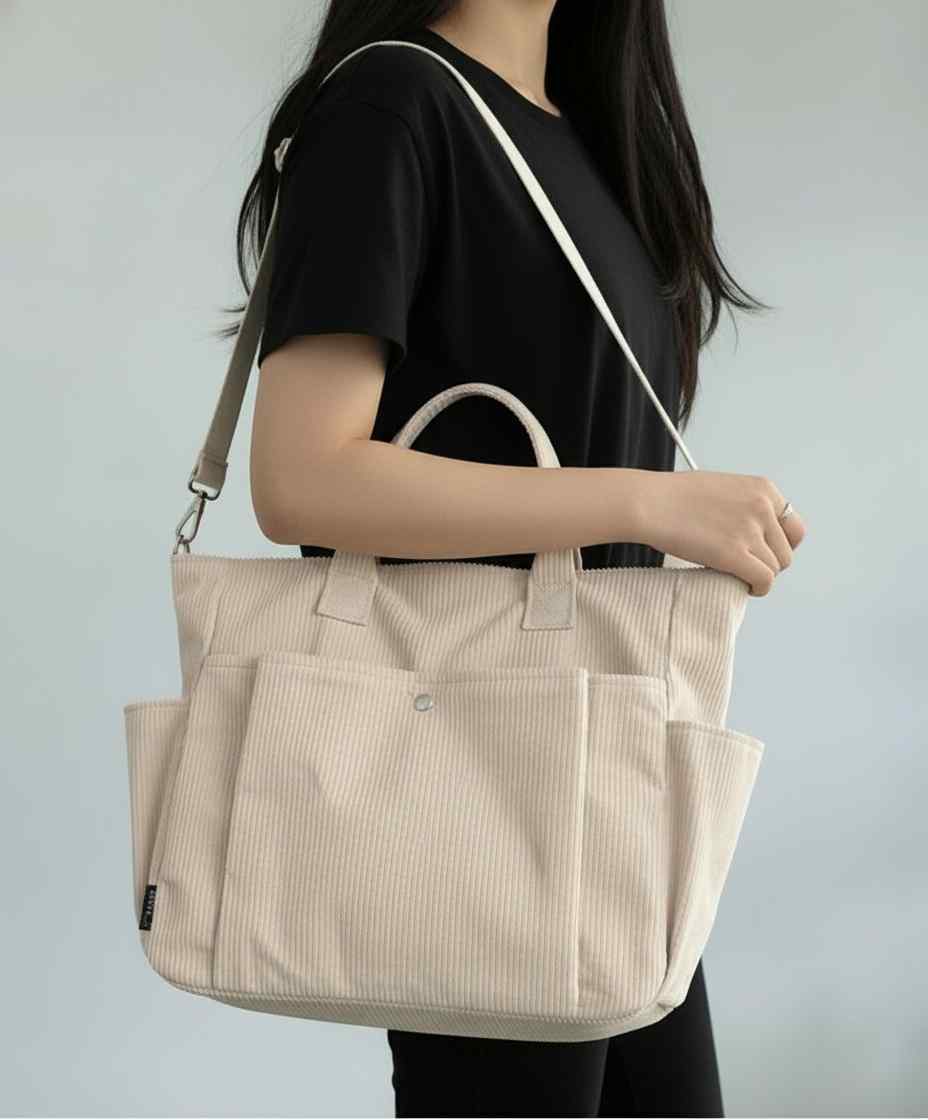 Person holding a beige tote bag against a plain background