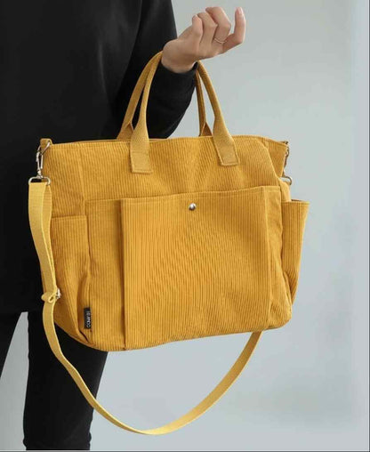 Yellow corduroy bag held by a person against a light gray background